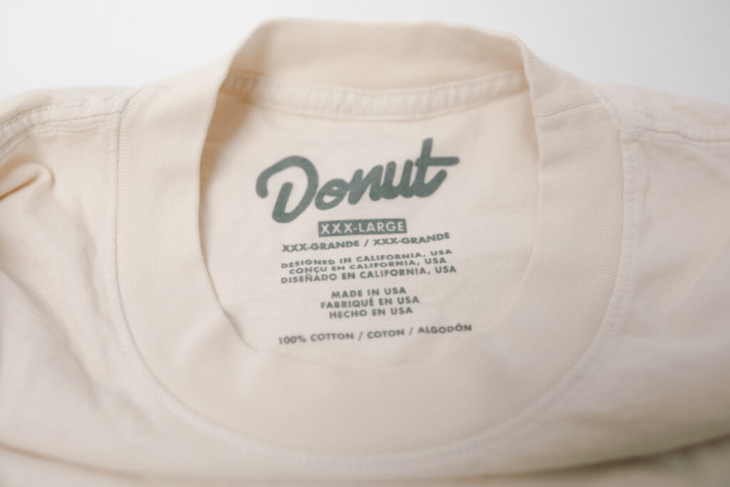 Printed neck label inside a cream t-shirt, part of retail-ready finishing at From The Ashes Naples